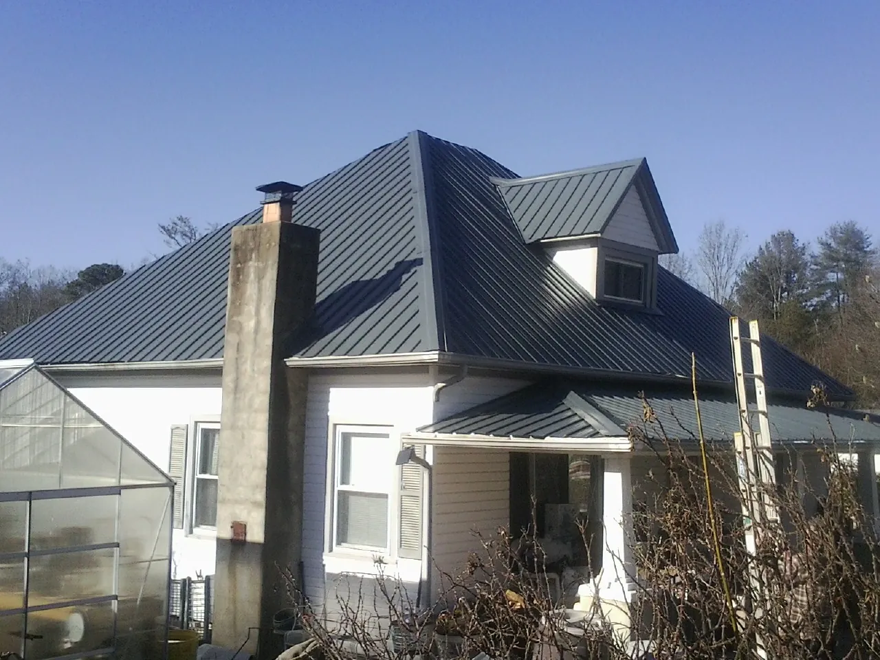 Dark blue standing seam metal roof on a white farmhouse with dormer — Slate & Tile Roof Repair by Roofing Brothers in Theodore