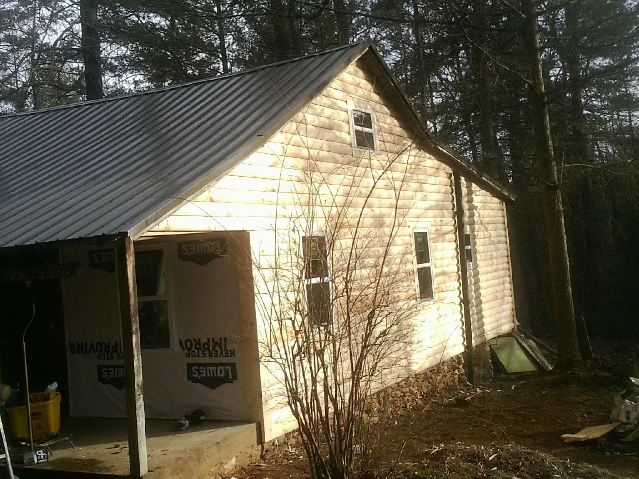 Log siding gable end under a dark metal roof edge in Theodore