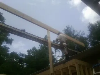 Carpenter setting a ridge beam over a new addition frame — Ice Dam Removal by Roofing Brothers in Theodore