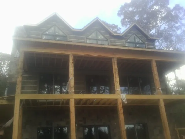 Dormers and porch framing on a large log home under construction — Roof Coating work by our crew in Theodore