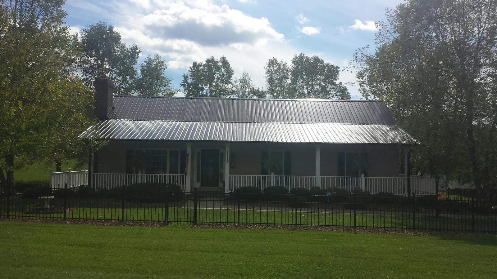 Gray metal roof on a brick ranch with a full width front porch — Gutter Guard Installation work by our crew in Theodore